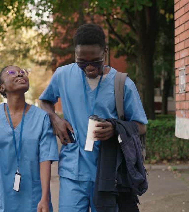 Two young friends wearing medical scrubs walking together in an urban area